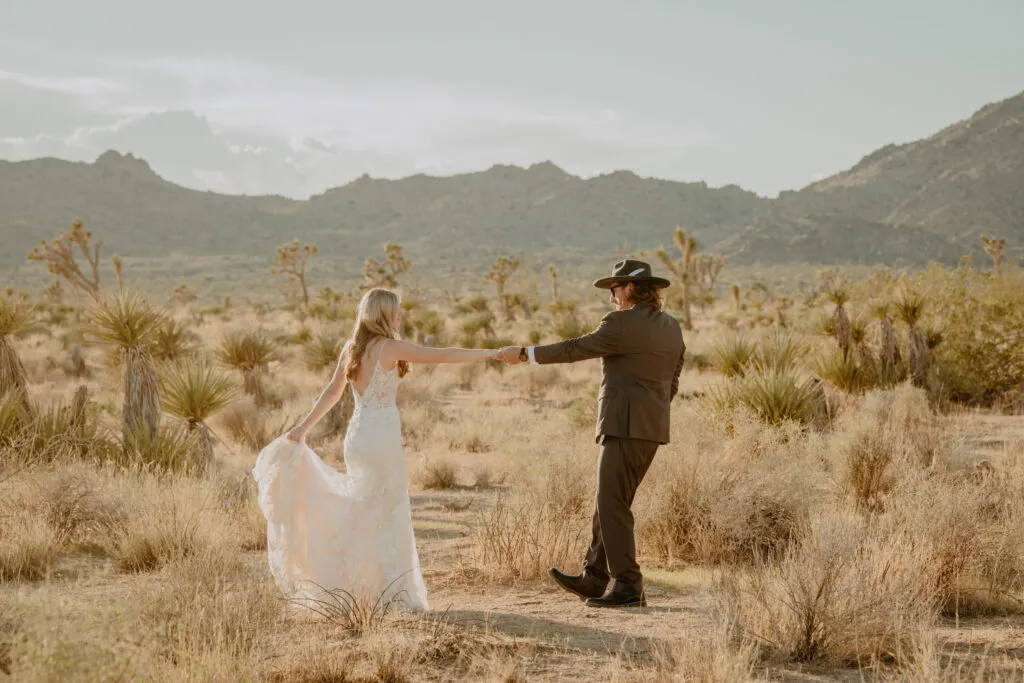 Bride and groom walking through Joshua Tree desert landscape at sunset