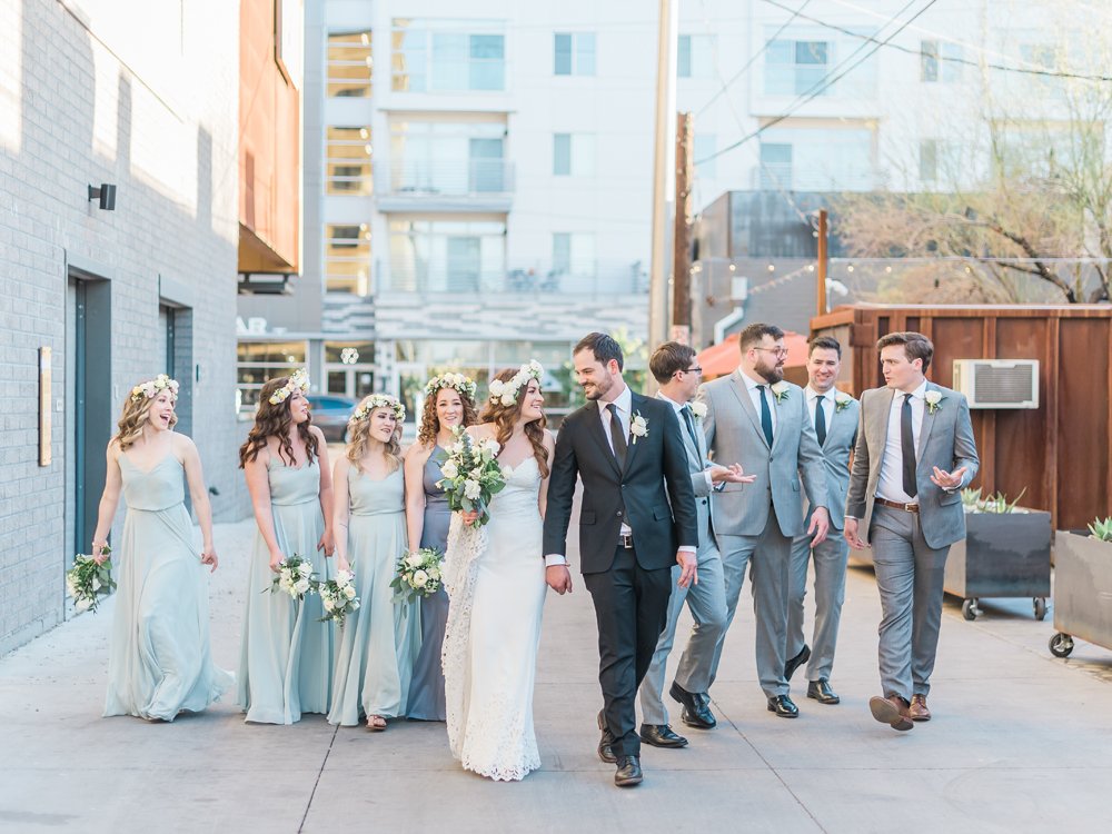 Wedding party walking through modern downtown Phoenix alleyway in elegant pastel attire