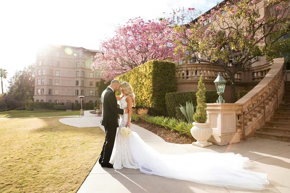 Historic Estate Garden Portrait in Pasadena Bride and groom at golden hour on a European-style estate lawn with pink blossoms and stone balustrades.