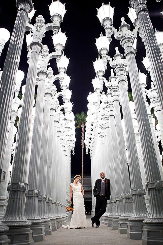 Elegant bride and groom walking through LACMA Urban Light installation at night during Los Angeles wedding