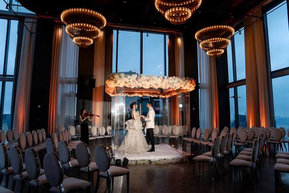 Waterfront Ballroom Ceremony with Panoramic San Diego Views Indoor ceremony in a glass-walled San Diego ballroom at dusk with floral chuppah and glowing chandeliers.