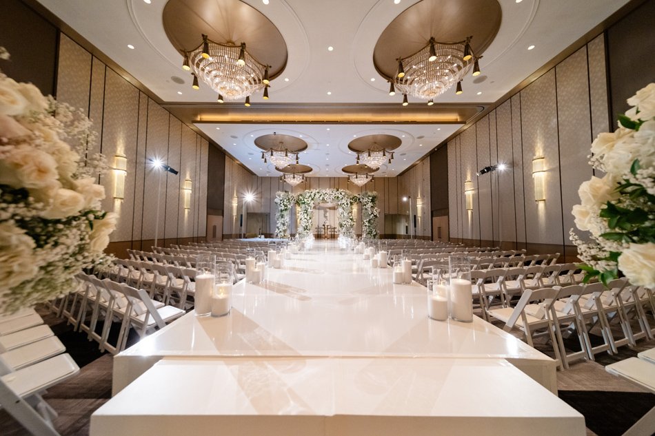 Luxury Hotel Ceremony With Gloss Aisle Runway Grand hotel ceremony with glossy white aisle, candles, and suspended chandeliers.