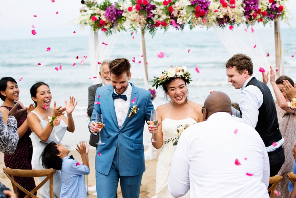 Confetti-filled beach ceremony exit in Southern California with tropical florals, smiling guests, and ocean backdrop.