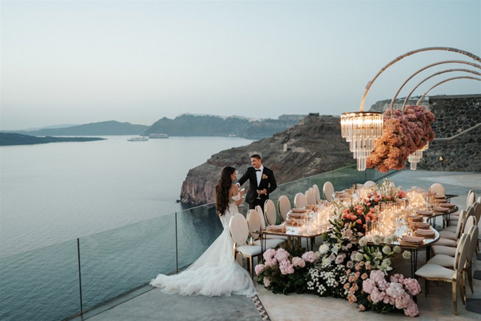 Luxury Southern California cliffside wedding dinner with chandeliers, pastel florals, and glass railing over the Pacific.