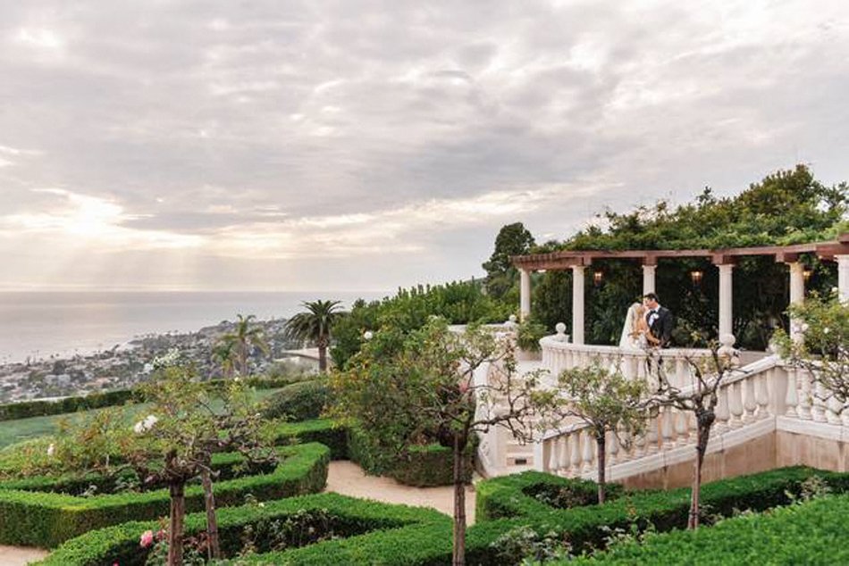 Laguna Beach Estate Terrace with Ocean Views Bride and groom on a Laguna Beach estate terrace overlooking the ocean and sculpted hedges.