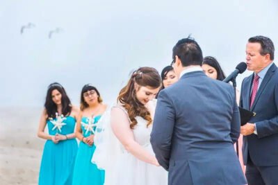 Emotional vow exchange on the sand with Pacific Ocean backdrop