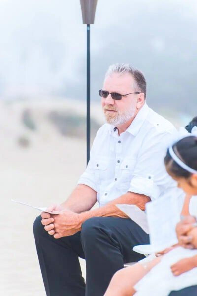 Bride smiling while holding bouquet of white roses and eucalyptus
