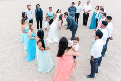 Guests seated on beach, surrounded by palm trees and ocean air