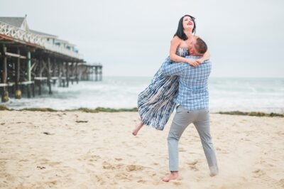 Groom lifts bride on the beach at sunset — Southern California coast — Lovelee Photography