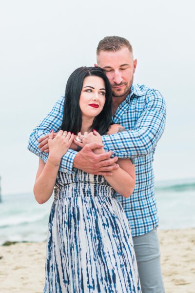 Close embrace at the waterline with pastel sunset sky in San diego engagement session