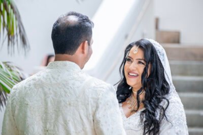 Bride smiling up at her groom during a first look moment in soft natural window light.