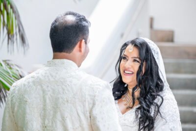 Closeup of South Asian bridal bouquet with pastel roses, orchids, and henna-adorned hands with bangles.