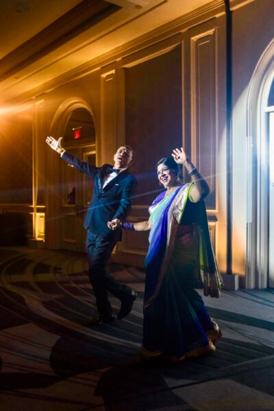 Bride twirling in a blue evening gown as she and the groom enter the ballroom reception.