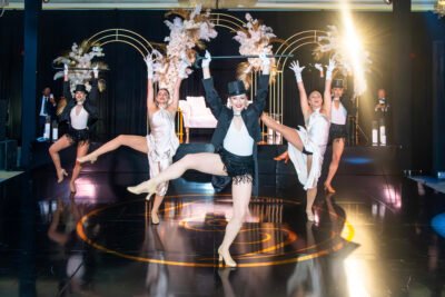 Dance troupe in black and white costumes kicking in unison during a high-energy wedding show.